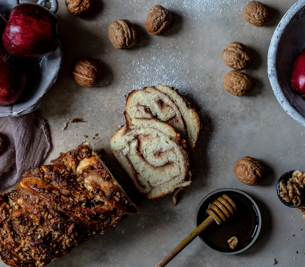 Slices of apple and honey babka with red apples and walnuts.