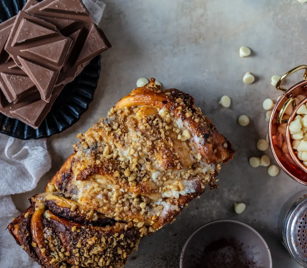 Close crop of half and half babka with its nut crumble and white chocolate chips.